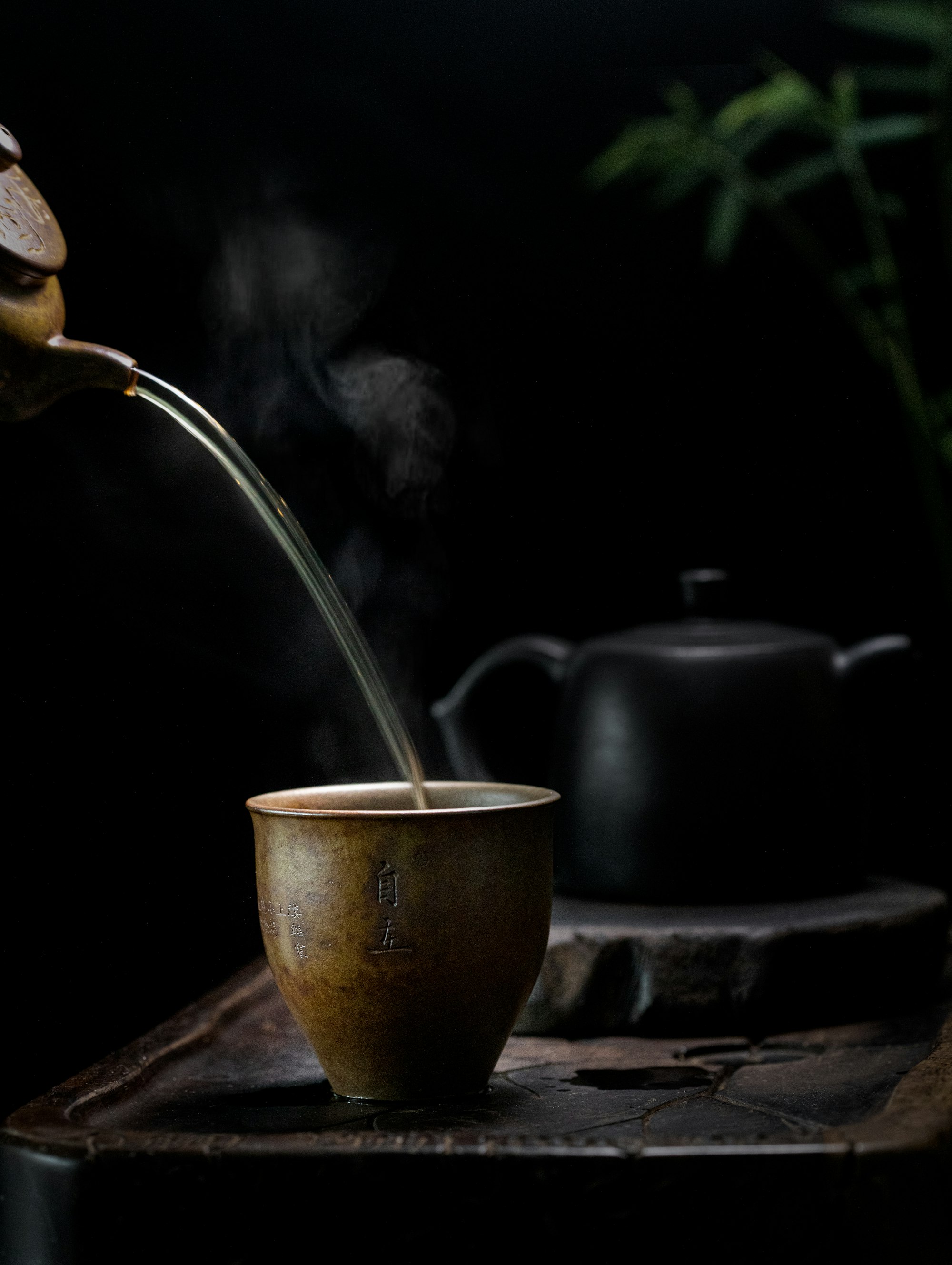 Brass kettle pouring tea into a ceramic cup