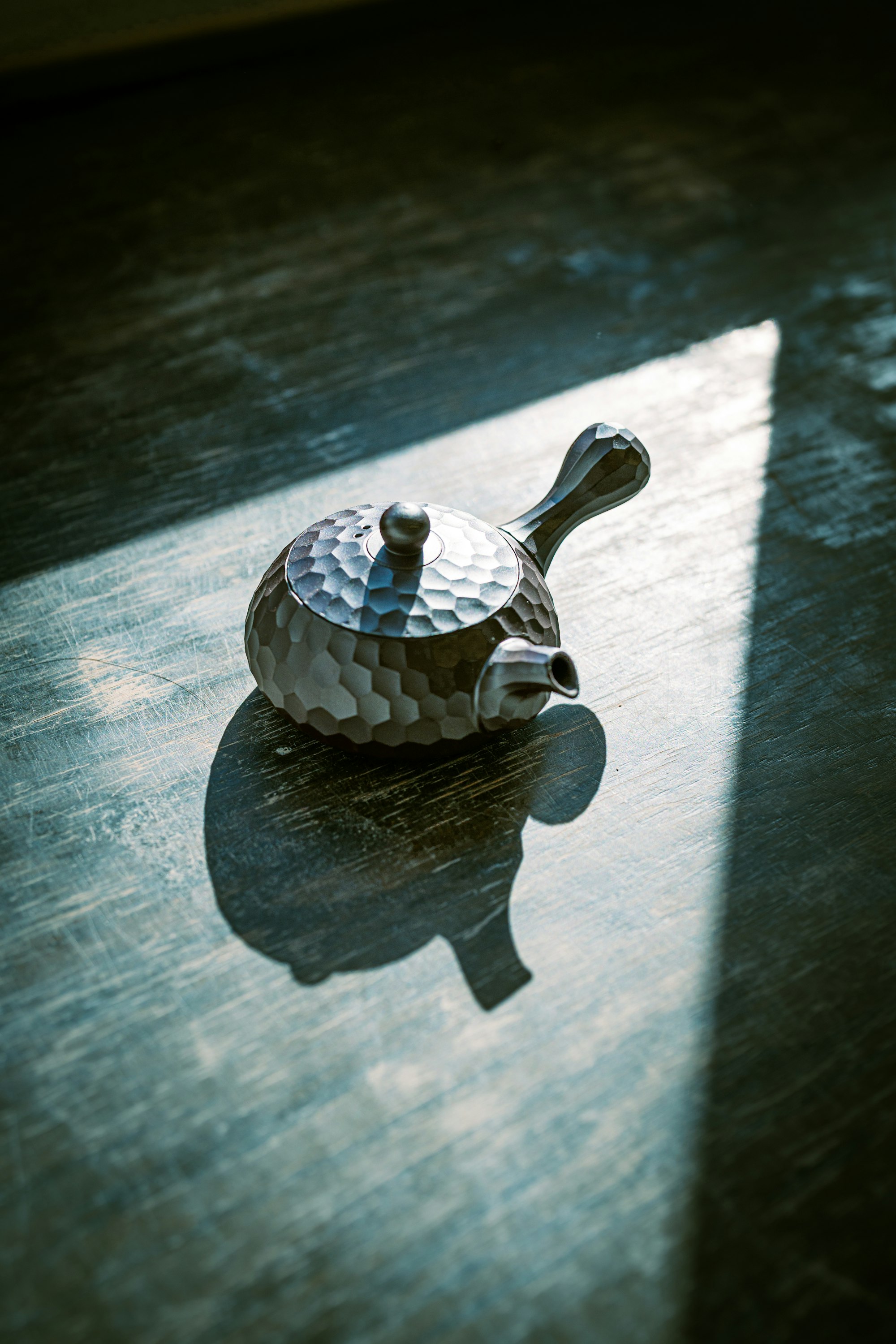 A hammered teapot catching low sunlight